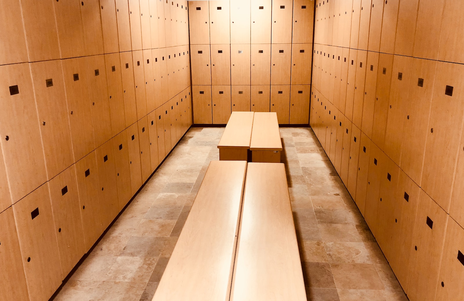 four brown wooden benches inside locker room